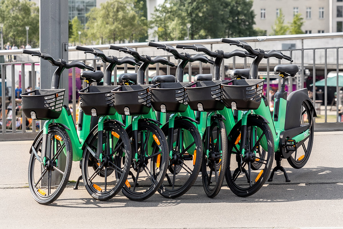 A row of green bicycles parked in front of a building, showcasing the future of micromobility.