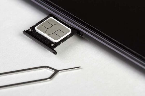 A close-up of a partially ejected SIM card tray with a SIM card inside and an ejector tool next to it.