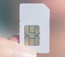 A person holding a traditional SIM card in their fingers.