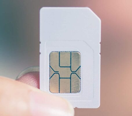 A person holding a traditional SIM card in their fingers.