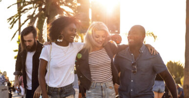 A group of friends are walking down the street at sunset.