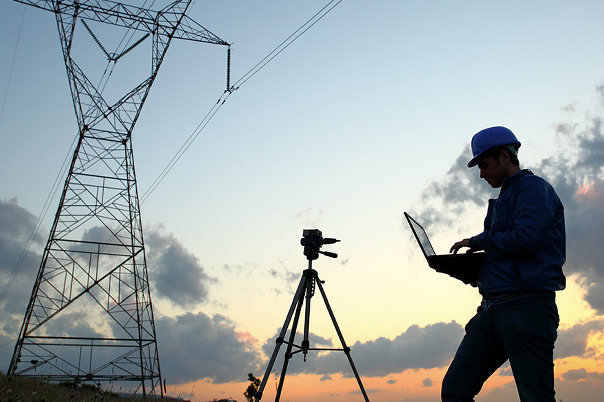 A man with a laptop in front of Telit power lines.