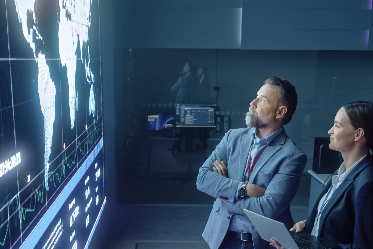 Two business people analyzing a map on a screen.