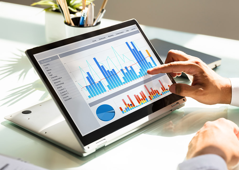 A man is pointing at a graph on a laptop, showcasing data from an IoT network.