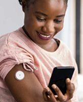 Woman checking glucose levels on her phone, leveraging Bluetooth wireless technology.