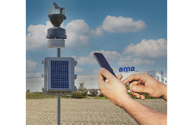 A person holding a cell phone next to a solar-powered IoT weather station for smart farming.