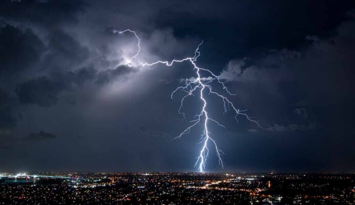 Lightning strikes over a city at night, creating a dazzling display of nature's power.