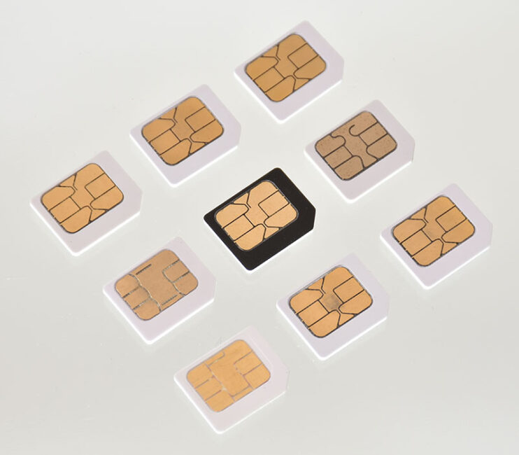 A photo of nine traditional SIM cards, with eight white SIMs surrounding a black SIM in the middle.
