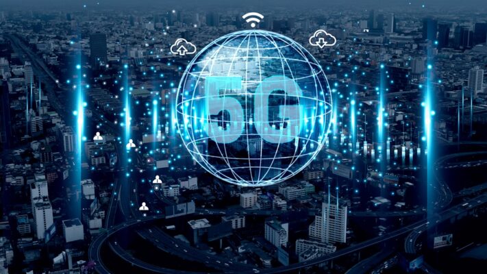 The word “5G” in a globe grid with cloud and connectivity icons overlaid on an aerial cityscape.
