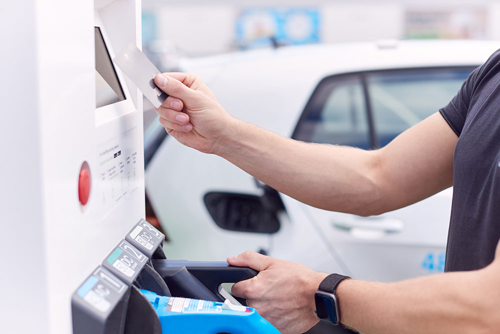 A person making a credit card payment at an EV charging station.