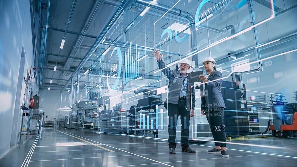 Factory digitalization: Two industrial engineers using a tablet computer and visualizing a wall of big data statistics.