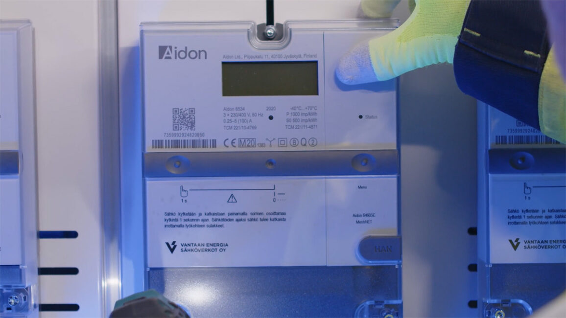 Aidon meter installation with hand in a yellow glove.