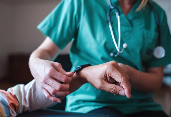 An elderly woman is fitted with a smartwatch for remote monitoring of vital signs.