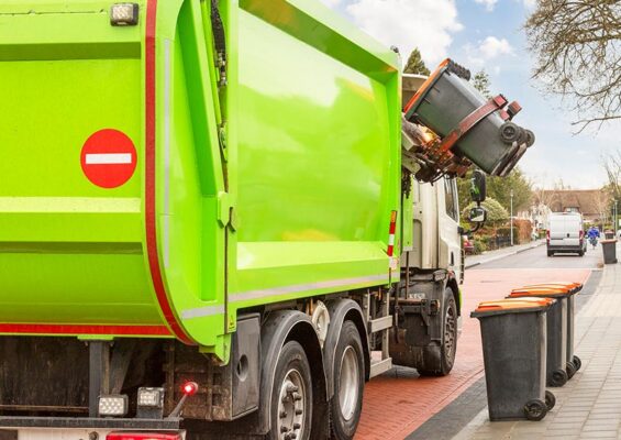 A trash bin is emptied into a garbage truck.