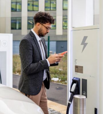 A man checks his phone while his EV charges.