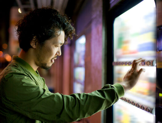 A person selecting a product from a smart vending machine at night.