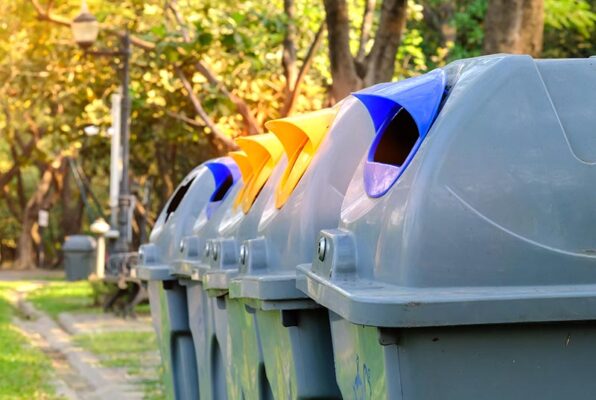 Waste and recycling bins along a walking path.