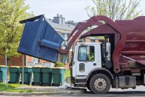 A garbage truck empties a large bin.