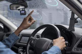 Driver interacting with a futuristic car's head-up display interface.