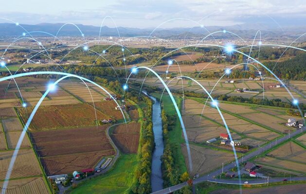 Aerial view of agricultural fields with digital network lines and nodes that illustrate connectivity and communication.
