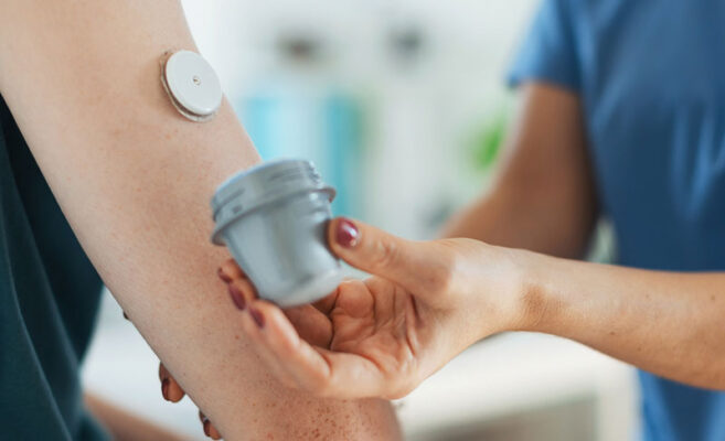 A person applies a medtech sensor to someone's arm, possibly for health monitoring.