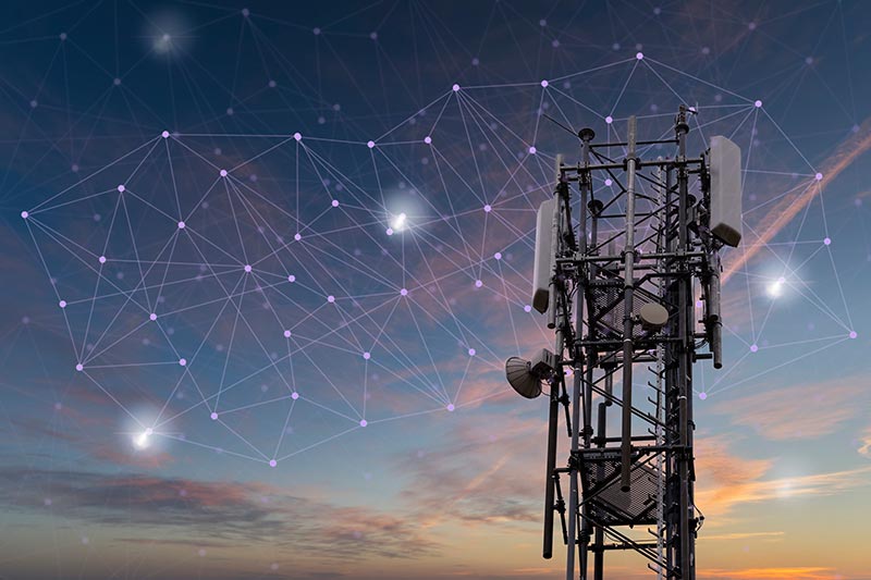A telecommunications tower against a sunset sky, with a digital network overlay illustrating connectivity.