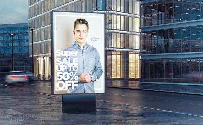 An advertising billboard on a busy city street displays a person promoting an exciting sale.