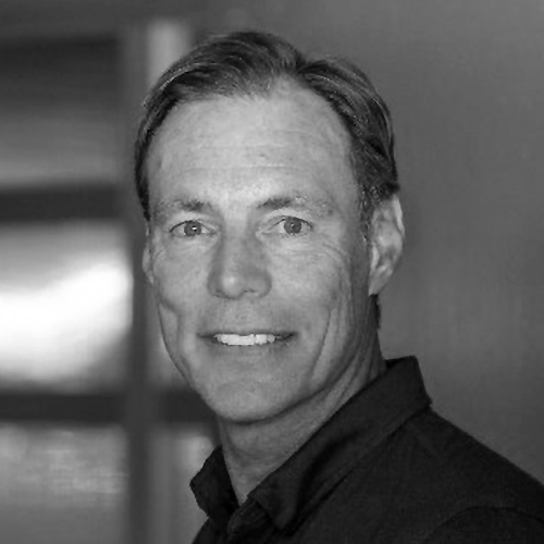 Black and white portrait of a middle-aged man with short hair, smiling at the camera, wearing a collared shirt.