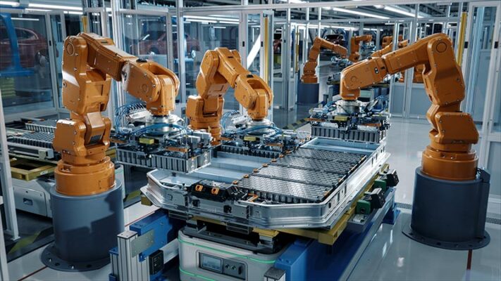 Robotic arms guided by IIoT systems management assembling components on a production line in a modern industrial facility.