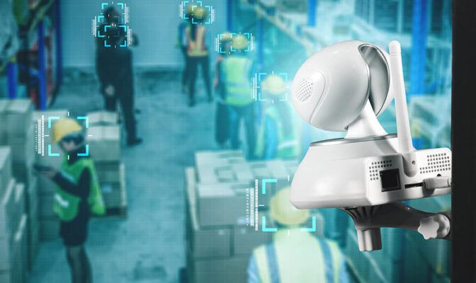 The security camera, enhanced with AI visual inspection capabilities, uses facial recognition technology to efficiently monitor individuals in a warehouse setting.