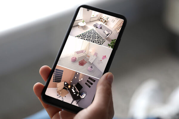 A person viewing a living room, child's bedroom and office space on a smartphone. 