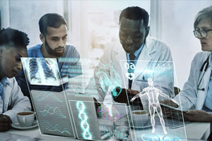 Four medical professionals engage in a discussion around a digital display, showcasing human anatomy and data overlays.
