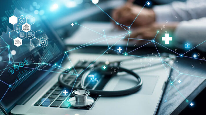 Digital icons overlay a laptop with a stethoscope resting on the keyboard, while a person writes on a notepad in the background.