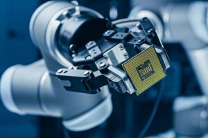 A robotic arm holding a computer processor chip in a technology lab setting.