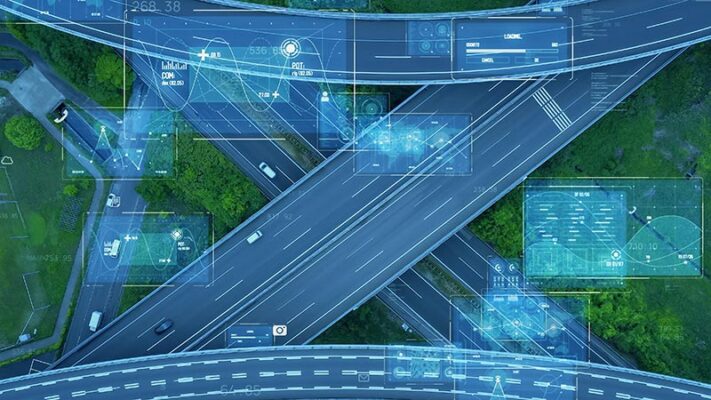 Aerial view of a highway interchange with digital graphics overlaying data and maps.