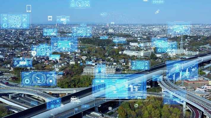 Aerial view of highways with digital graphics overlay showing data, maps, and IoT telematics analytics, representing smart city technology over an urban landscape.