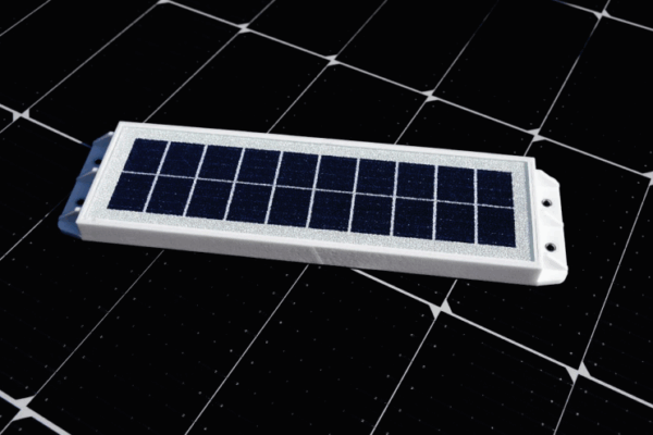 A small rectangular telic solar panel device rests on a larger grid of solar panels.