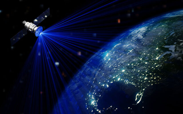 A satellite orbits above Earth, emitting blue signals toward the planet’s surface, where vibrant city lights illuminate the land below.