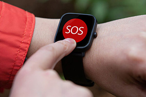 A person presses the large red "SOS" button on a smartwatch screen.