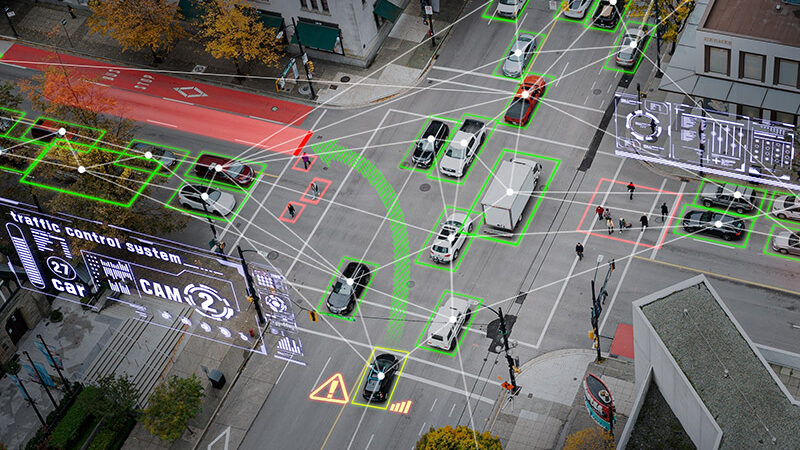 Vehicles surrounded by green rectangles travel through a city intersection. A simulated traffic dashboard is on the left side.