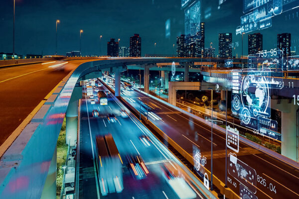 A city highway at night with blurred car lights, overlaid with digital graphics, indicating a smart city.