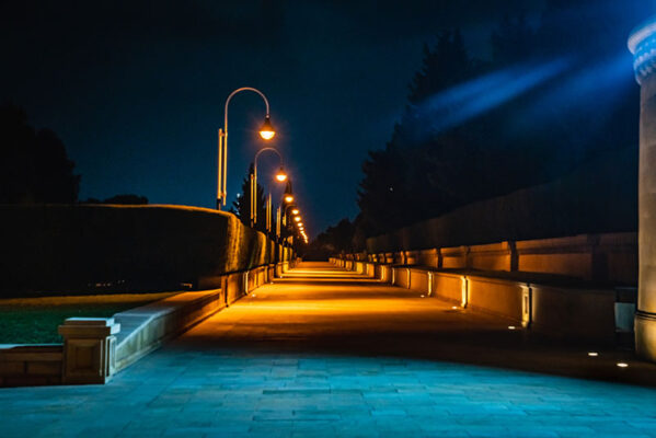 A paved pathway illuminated by a row of streetlights at night.