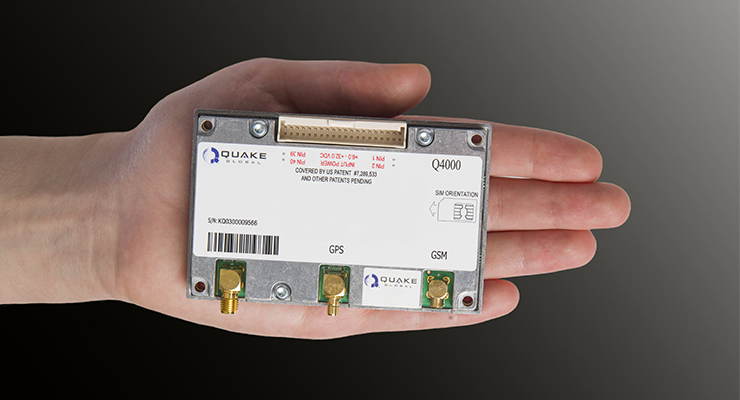 A person holds a rectangular electronic device labeled "Quake Q4000" with visible GPS and GSM ports against a gradient background.