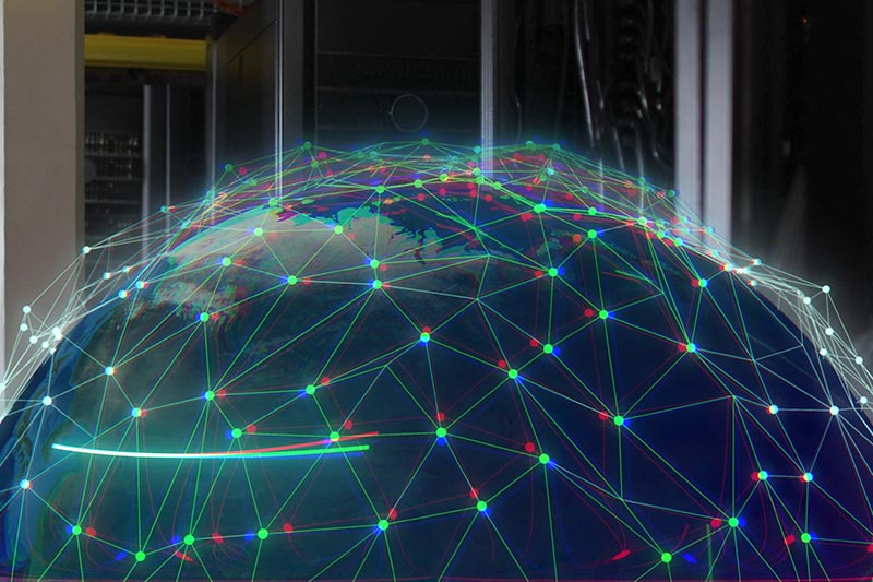A digital rendering of Earth with network nodes and lines, symbolizing global connectivity, is superimposed over computer servers.