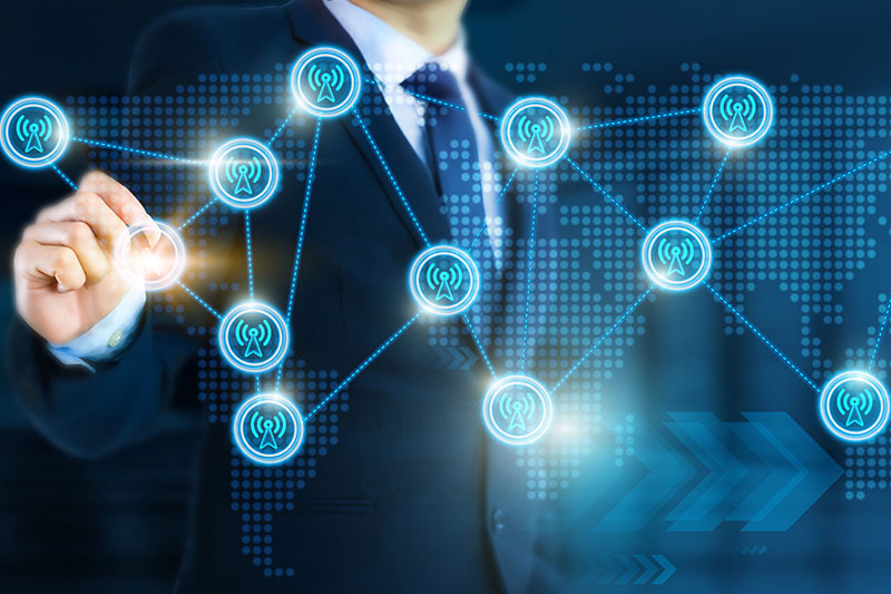 A person in a suit interacts with a virtual touchscreen displaying interconnected wireless network icons over a world map.
