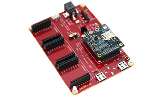 A red microcontroller development board with multiple black pin headers and a smaller blue circuit board mounted on top.