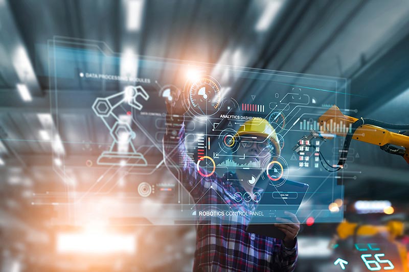 A person in a hard hat interacts with a transparent digital interface displaying data analytics and robotic controls in a high-tech industrial setting.