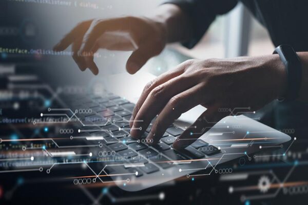 Hands typing on a laptop keyboard with digital data graphics and code overlays, suggesting technology or software development.
