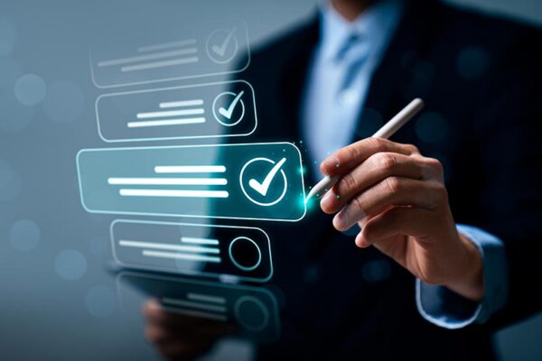 Person in a suit using a stylus to interact with digital checkboxes on a transparent screen, with one checkbox marked.