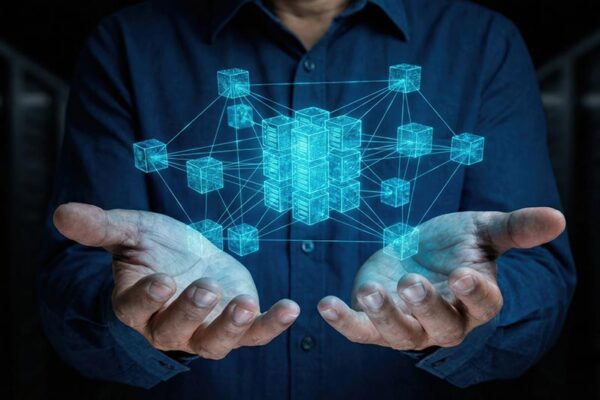 A person holds out their hands with a digital hologram of interconnected cubes floating above their palms.